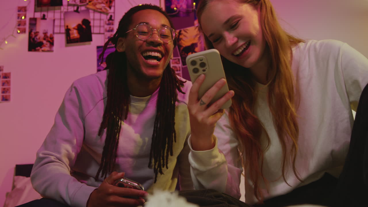 una pareja riendo de un video gracioso en su teléfono.