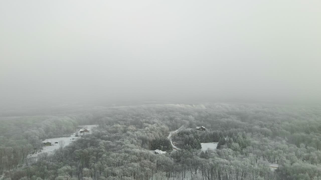 안개를 뚫고 눈으로 가득 찬 작은 마을을 드러내는 드론 뷰