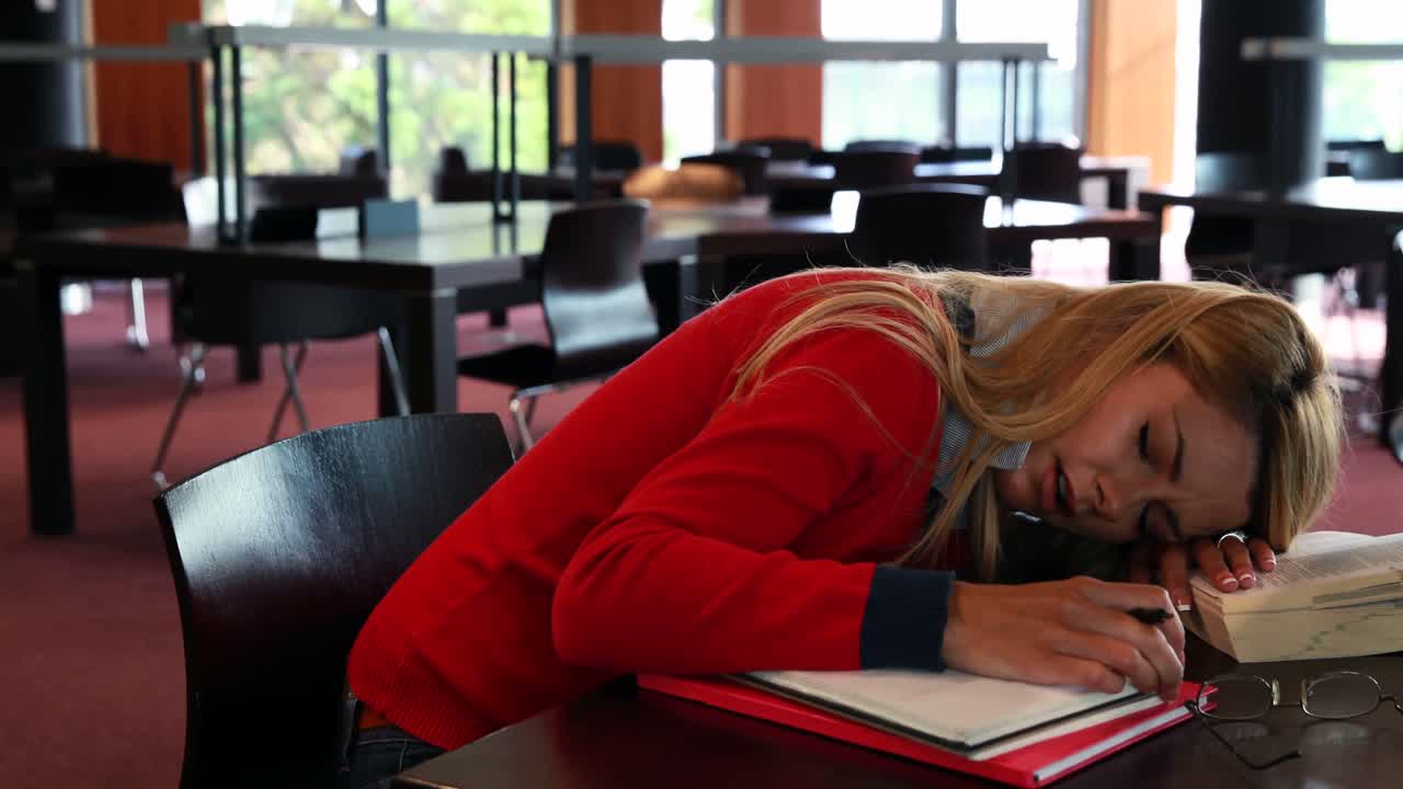 Voksen student sover ved studiepulten.