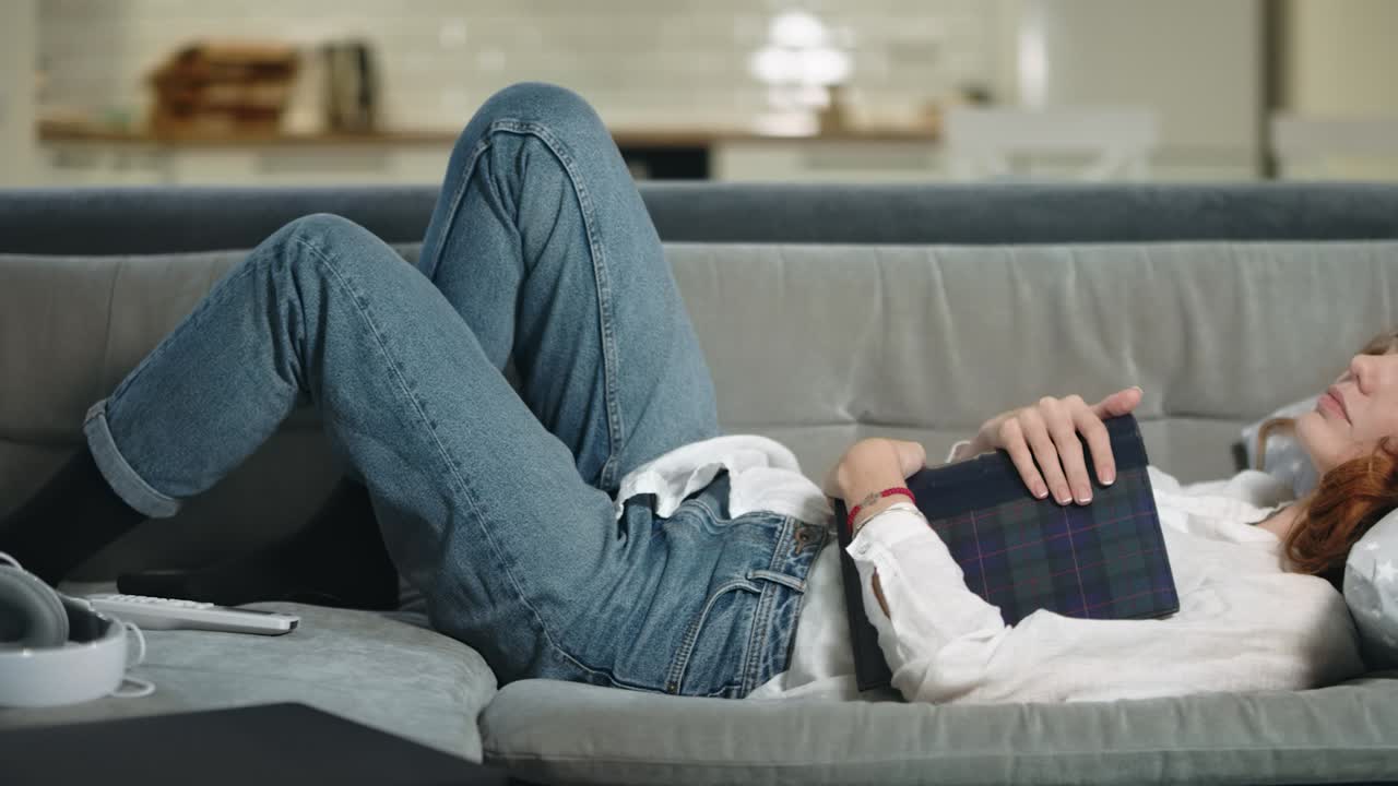 현대적인 부 ⁇ 에서 소파에서 잠을 자는 피곤한 여성. 편안한 여성이 사진 앨범을 안아