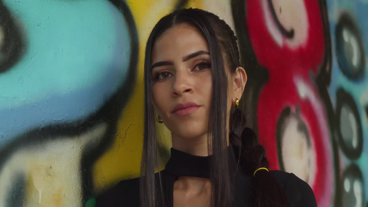 Facial close up of a young Latina in red heels inside a skate park warehouse.
