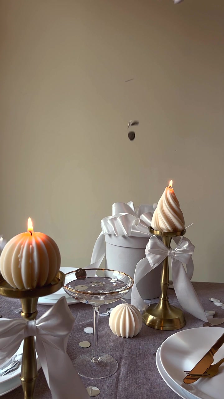 Tavola apparecchiata a festa con candele accese e coriandoli in caduta.