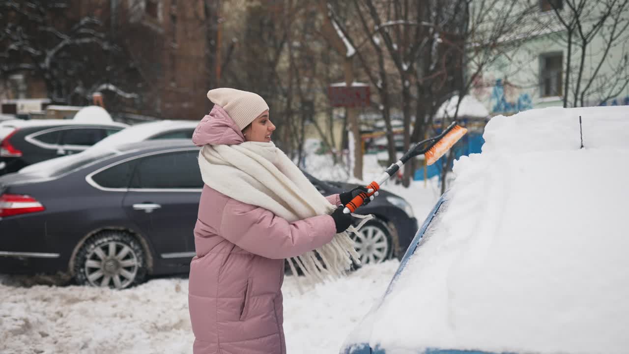 mujer quitando la nieve de un coche en invierno