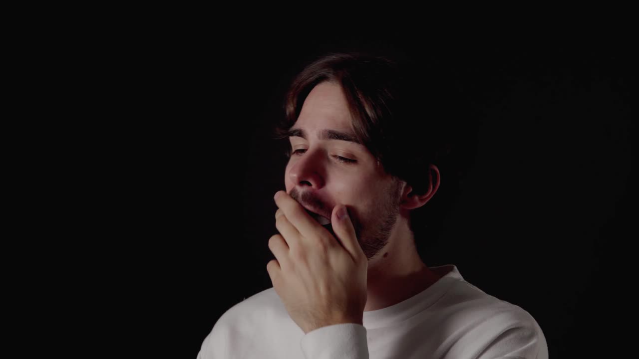Trendy Young Man yawning, tired gesture, close, black background