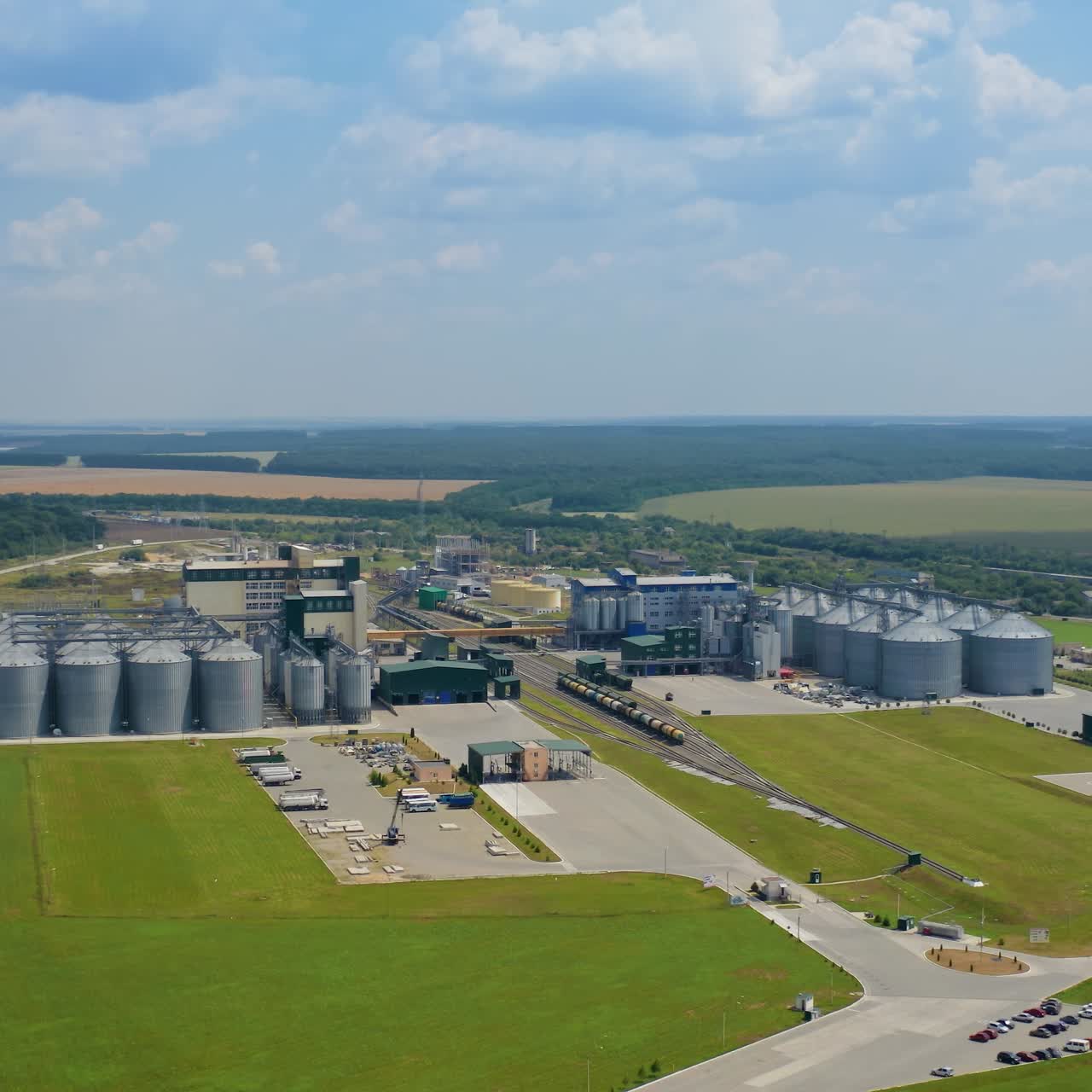 Neue Industrie in der Natur. Außenansicht eines modernen Getreidespeichers auf grünem Feld. Industrieanlage zur Lagerung und Verarbeitung von Getreide. Silo-Systemtanks. Luftaufnahme.