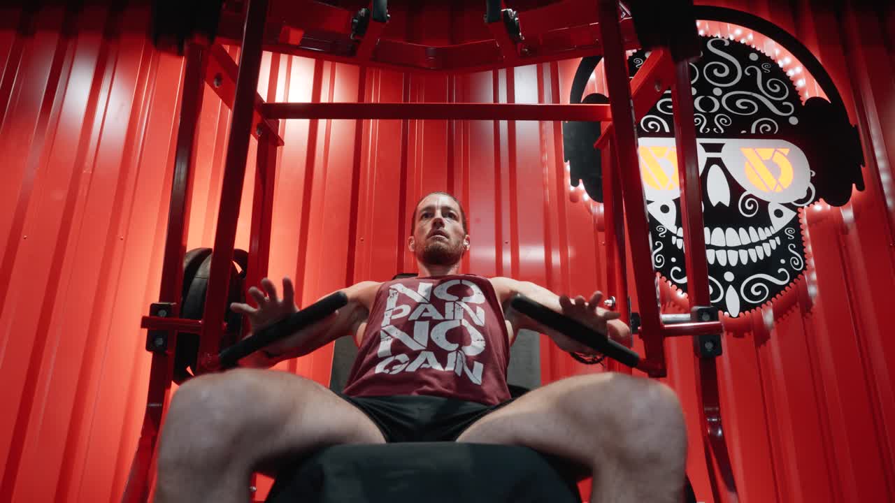 Primer plano de un hombre realizando un press de banca inclinado en máquina durante un entrenamiento