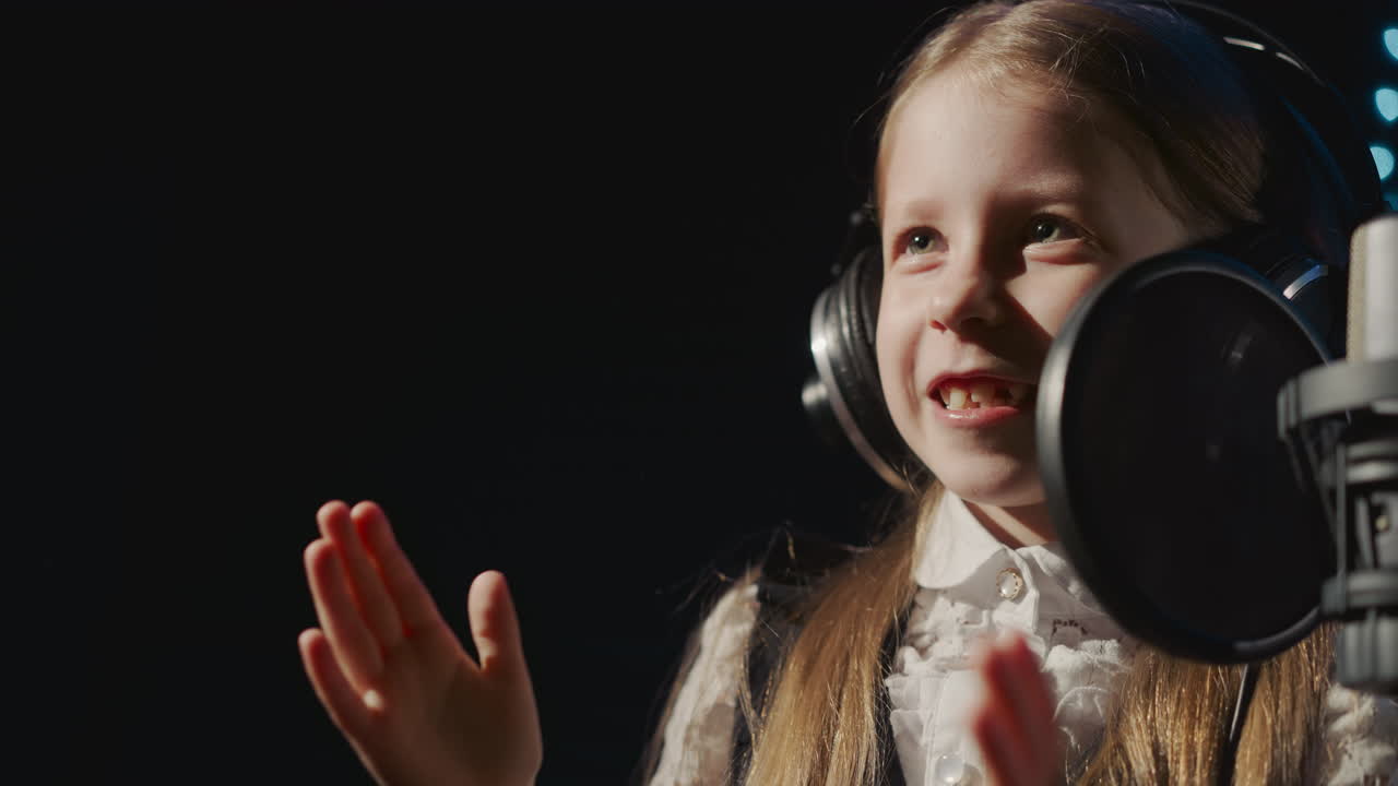 Child plays pat-a-cake with teacher in audio studio. Joyful little girl has fun with instructor taking break at vocal lesson. Informal studying