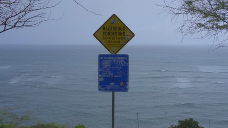 a sign warning of hazardous conditions on a cliff near the beach in hawaii