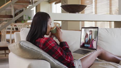 Mixed-race-woman-on-laptop-video-chat-having-coffee-at-home