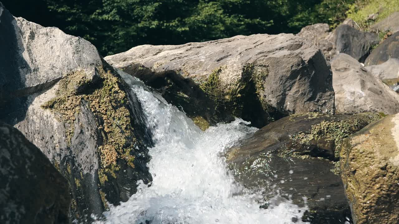 vista de cerca del agua cristalina que fluye sobre las rocas cubiertas de musgo en una hermosa cascada