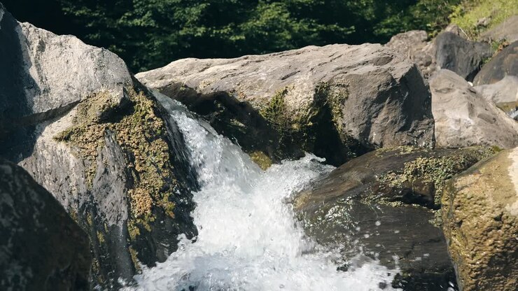 Close-up view of crystal clear water flowing over moss-covered rocks in a beautiful waterfall