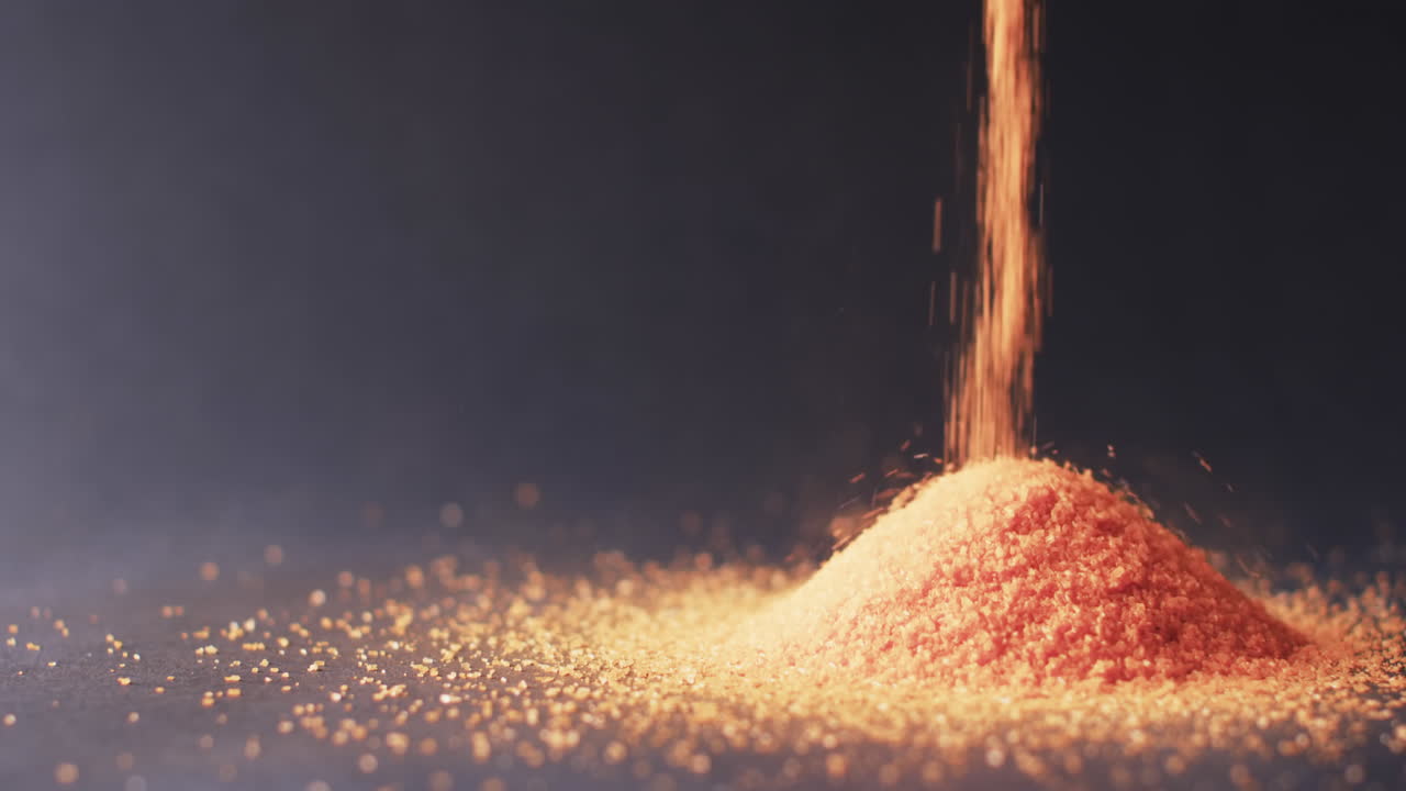 오렌지색 모래 알 ⁇ 이가  ⁇ 어져 검은색 배경에 있는 공간을 복사하는 클로즈업 비디오