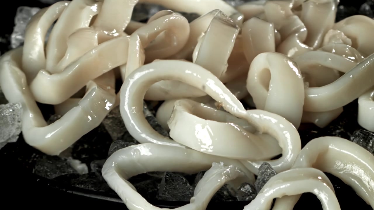 砕いた氷の上に新鮮な生のイカリングが落ちる