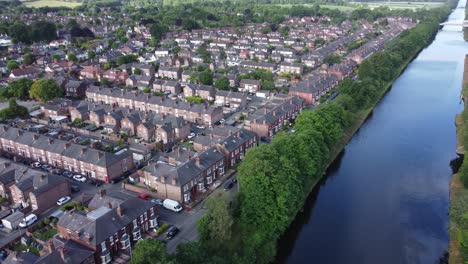 aerial view flying above wealthy cheshire housing estate alongside manchester ship canal descending pan right shot