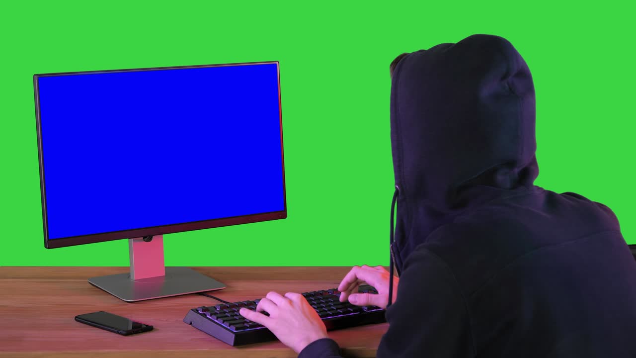Hacker in hood cracking code using pc on a Green Screen, Chroma Key