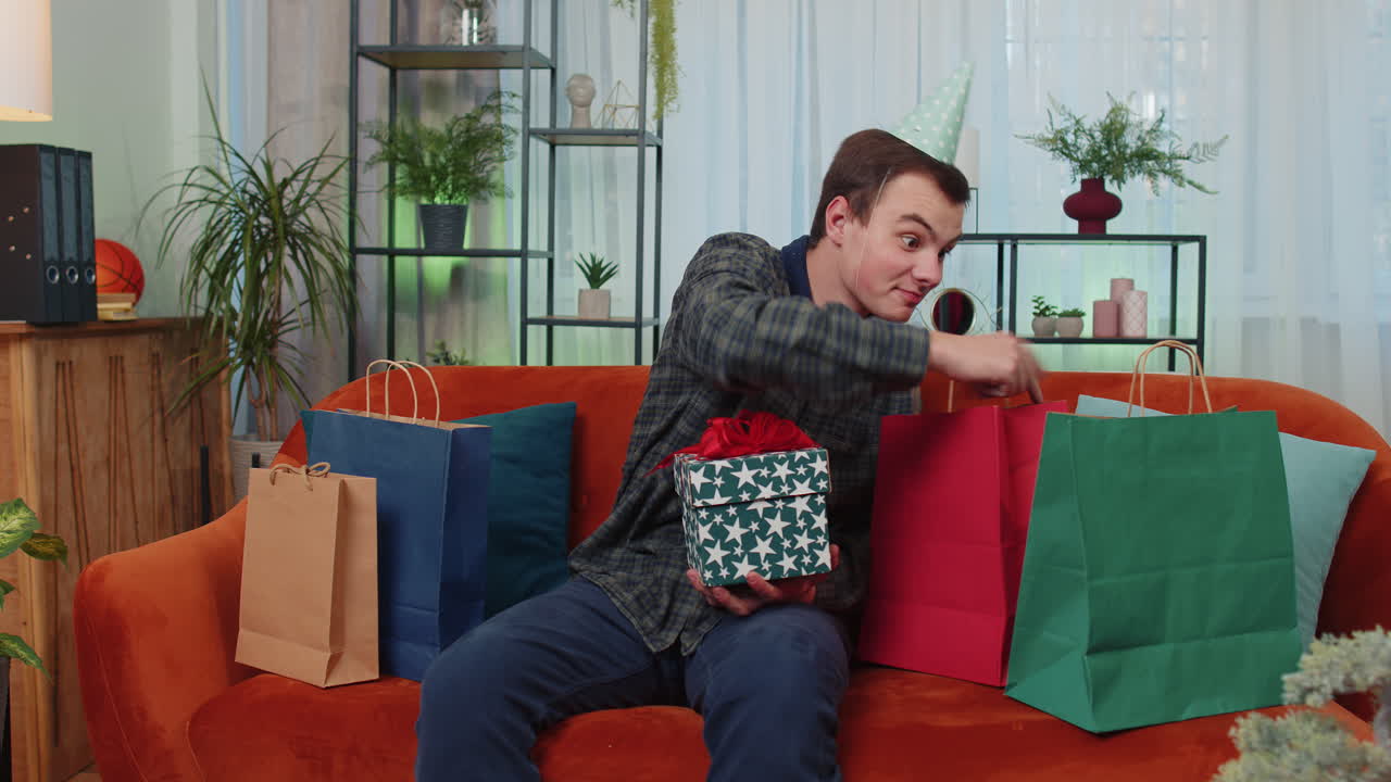 hombre adolescente feliz sostener caja de regalos de cumpleaños con cinta, celebración de la fiesta, apertura de regalo en casa