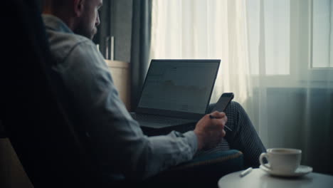 top view of anonymous mature male analyst in blue suit sitting at desk in corporate office, working on financial report on laptop, studying numbers and data on graphs and charts