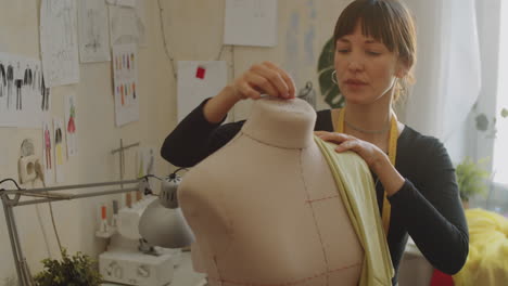 woman attaching fabric to dress form in atelier