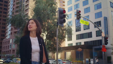 cheerful girl walking across road. asian lady looking around crossing street.