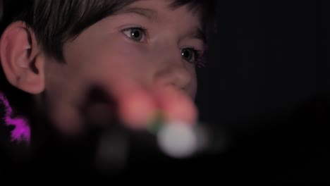un niño se sienta en la oscuridad frente a una computadora
