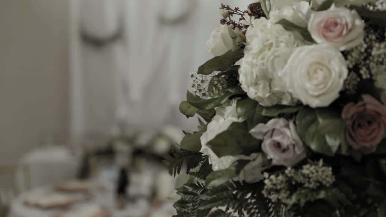 Head table reveal from behind a beautiful pink and white bouquet of roses
