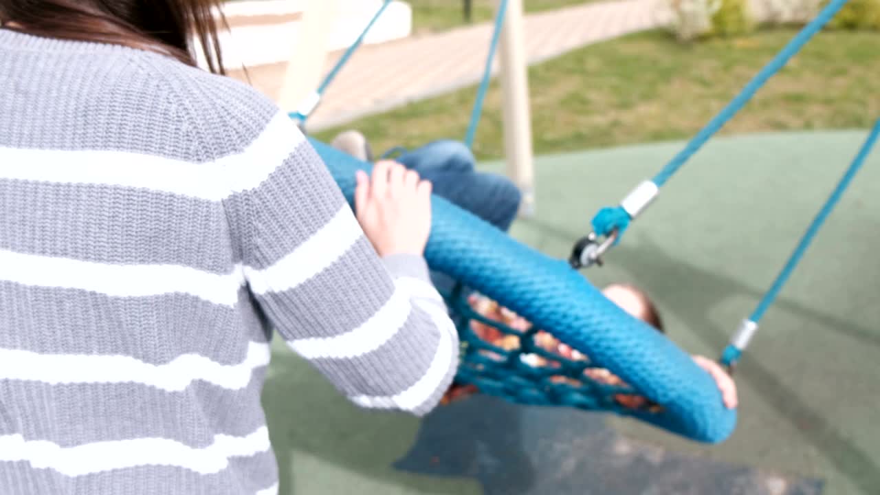 mamá y hijo en un columpio vacío.