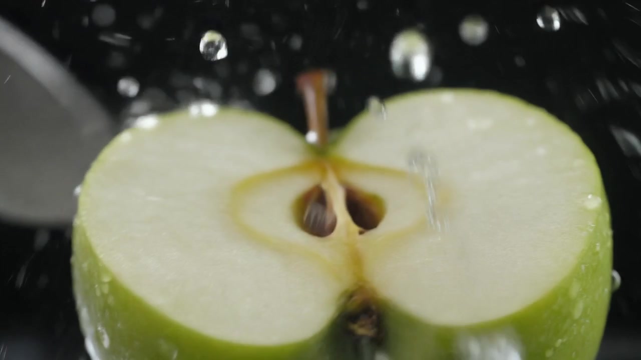 Coltello che affetta una mela verde fresca con schizzi d'acqua