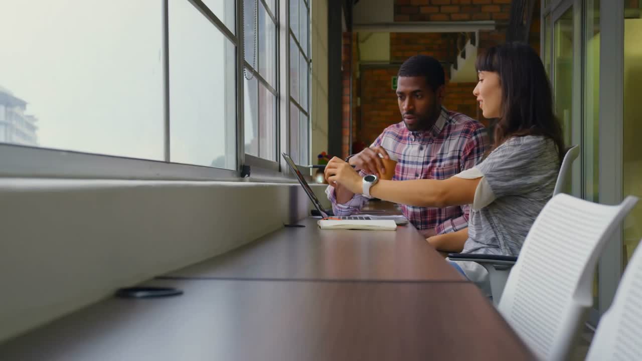 Männliche und weibliche Kollegen arbeiten gemeinsam am Schalter und zeigen animierte Netzwerksymbole für Technologie