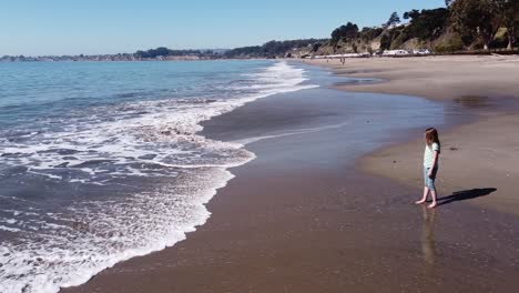 girl with long brown hair enjoys warm water of california coast in seacliff state beach