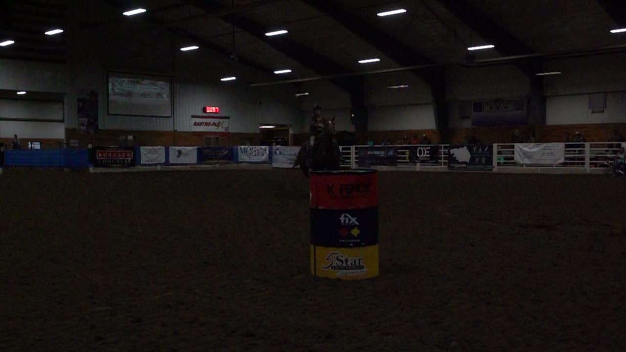 Cavaliere Equestre che Galoppa Attorno a un Barile in un'Arena Indoor