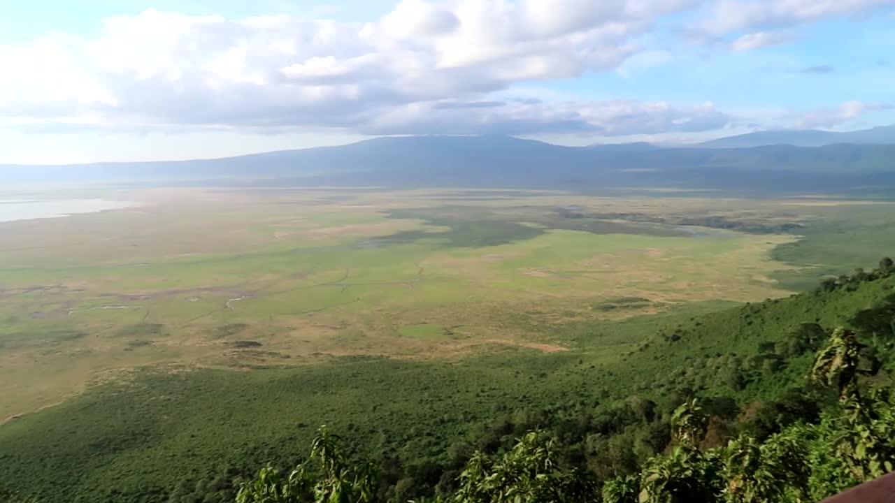 mujer joven fotografiando con un teléfono el maravilloso cráter volcánico verde del volcán ngorongoro