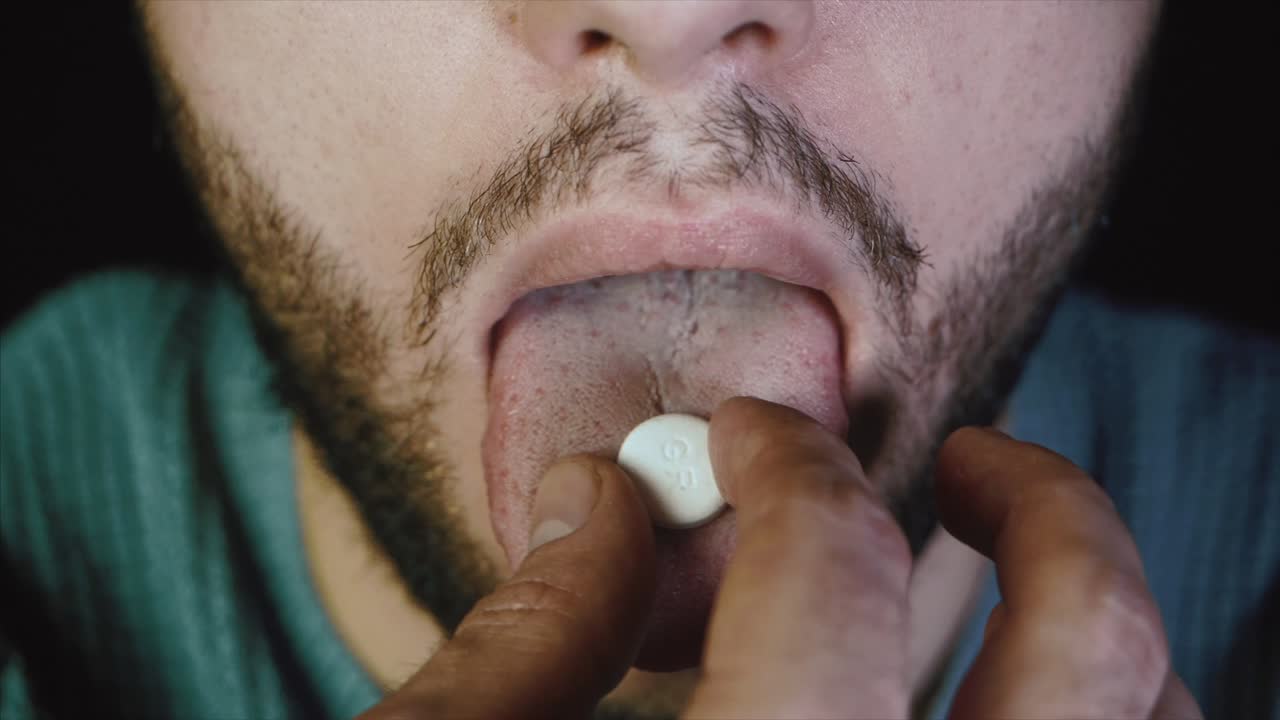 la boca del hombre con la lengua y la píldora