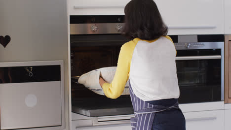 Video-of-happy-asian-woman-taking-out-cake-from-oven