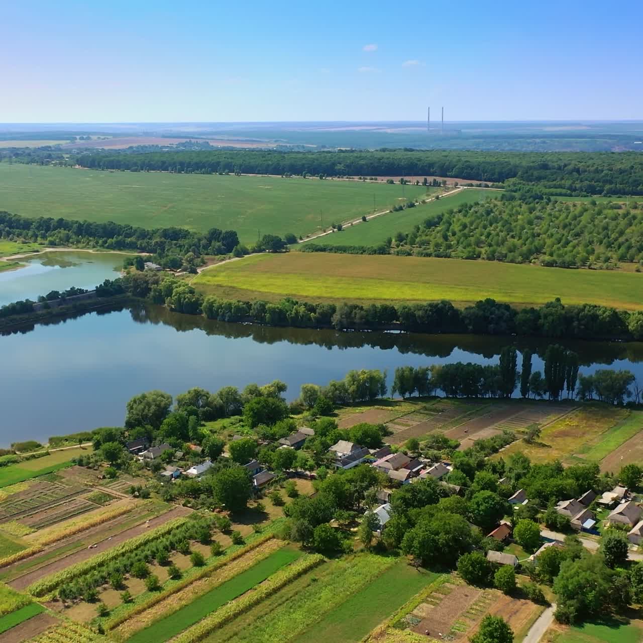 Little river floating in the green fields. Beautiful small village locating on the picturesque river bank. Top view