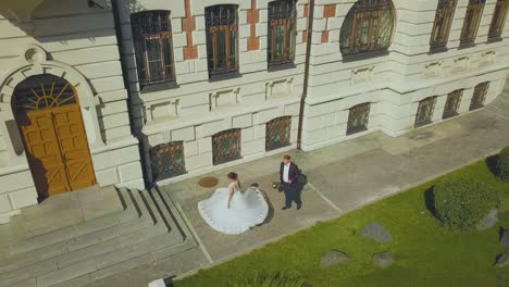 bride dances spinning near groom by building upper view