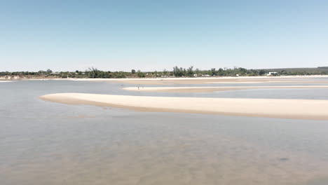 una pareja de pie en soledad en una gran playa con parches de agua clara y poco profunda