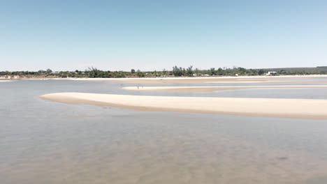 a couple standing in solitude on a vast beach with patches of shallow, clear water