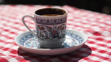 ornate turkish coffee cup on a checkered tablecloth