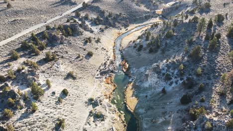 Drone-Inclinándose-Desde-Un-Arroyo-Hacia-Montañas-Nevadas-En-Las-Aguas-Termales-De-Wild-Willy