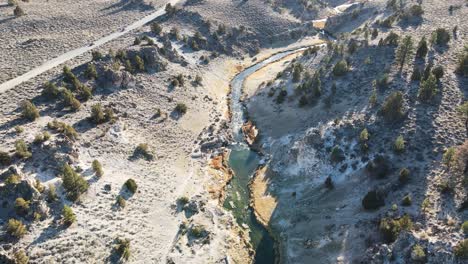 drone inclinándose desde un arroyo hacia montañas nevadas en las aguas termales de wild willy