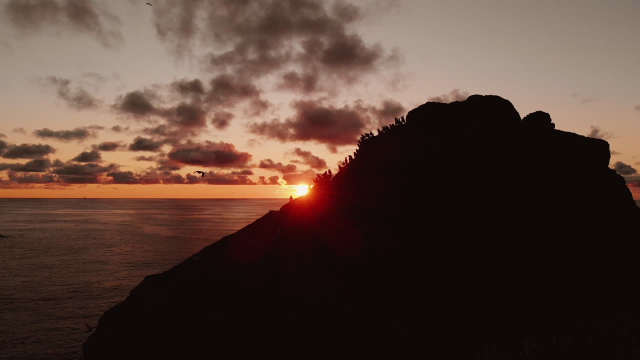 Sunset over a rocky cliff with people
