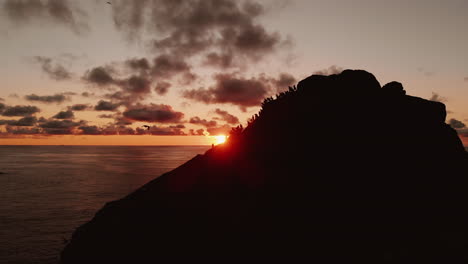 sunset over a rocky cliff with people
