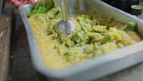 machacar y hacer puré de mandioca con una planta de hojas verdes para obtener un plato vegano orgánico elaborado con ingredientes de la selva amazónica