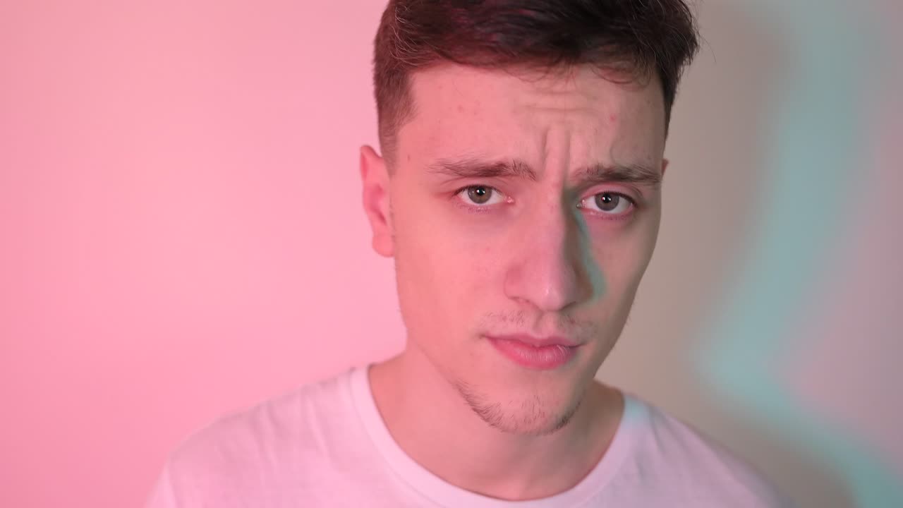 Young man putting black wireless earbud in the ear. Neon purple and blue light