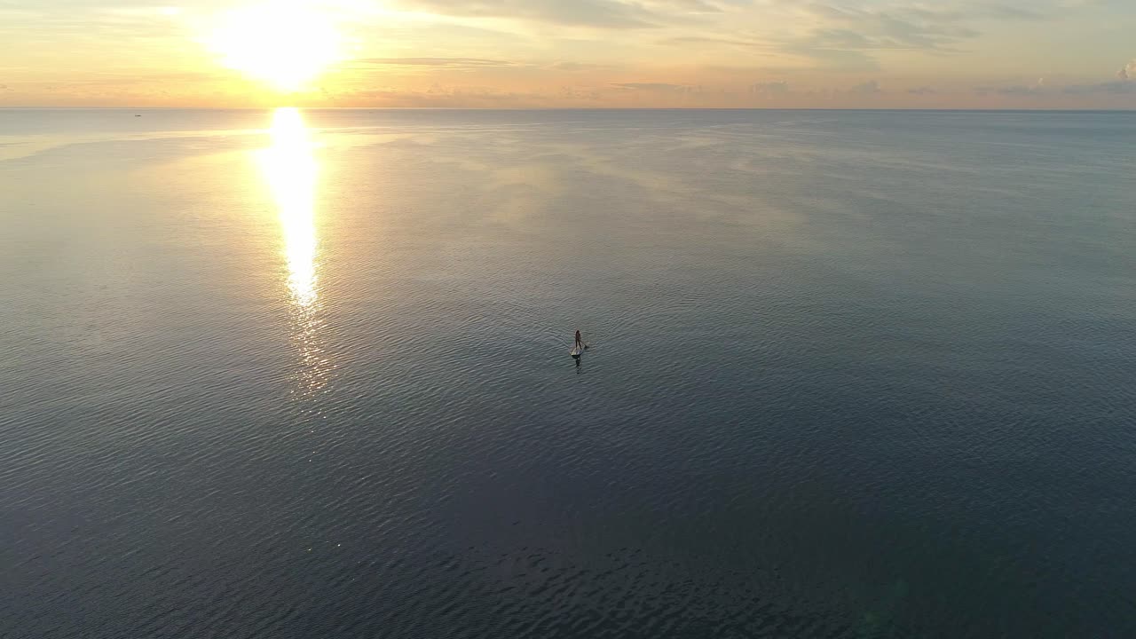 Woman Paddleboarding at Sunset