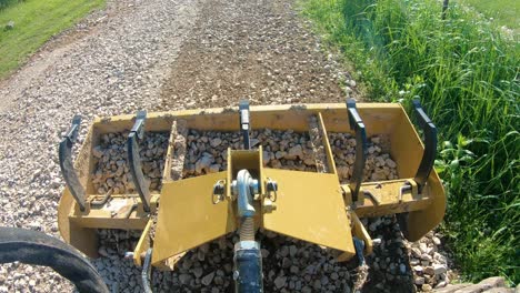 Box scrapper leveling a new graveled driveway and gravel that is in the box is distributed along the driveway