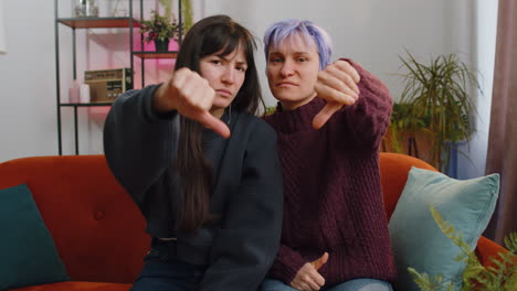 upset lesbian women family couple showing thumbs down sign gesture expressing discontent disapproval