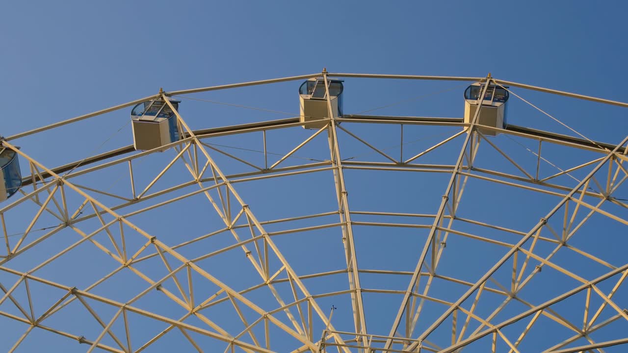 높은 페리스 이 하늘을 배경으로 회전하고, 사람들이 앉아있는 부스는 팬에 흔들리고 있습니다.