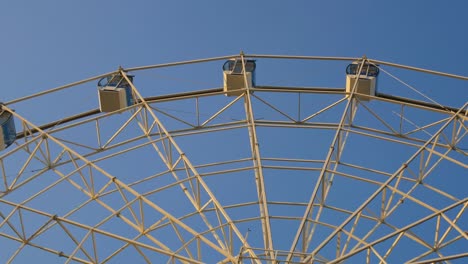 una alta rueda de ferris está girando contra el fondo del cielo, las cabinas en las que la gente está sentada están balanceándose en un abanico. paseos irreconocibles en un parque de atracciones o feria
