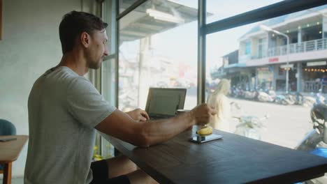 man working on laptop in a cafe with street view